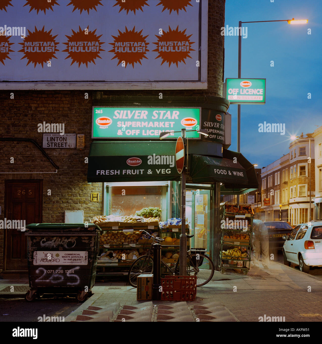 Esterno il crepuscolo colpo di late night convenience store North London inc Islington Consiglio bidone dei rifiuti shop produrre street display Foto Stock