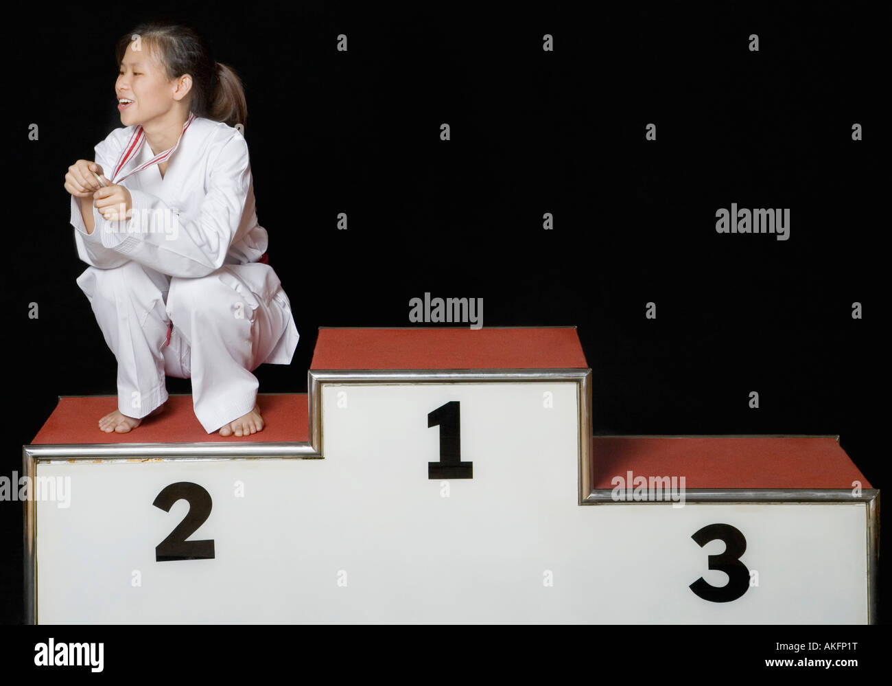 Giovane donna seduta su un podio dei vincitori con la sua medaglia Foto Stock