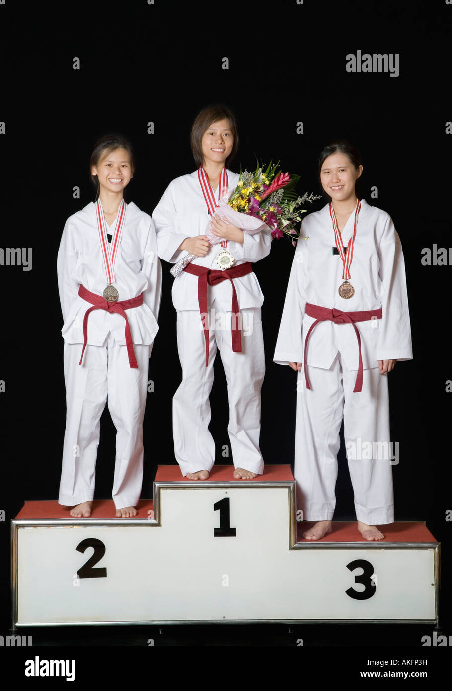 Tre giovani donne in piedi su un podio i vincitori con le loro medaglie e sorridente Foto Stock