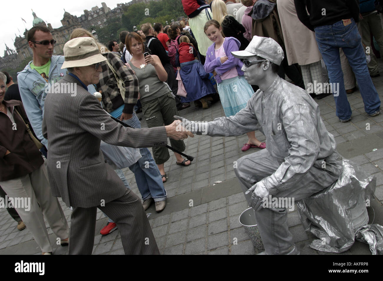 Un esecutore di strada scuote le mani con un turista al Festival di Edimburgo in Scozia Foto Stock