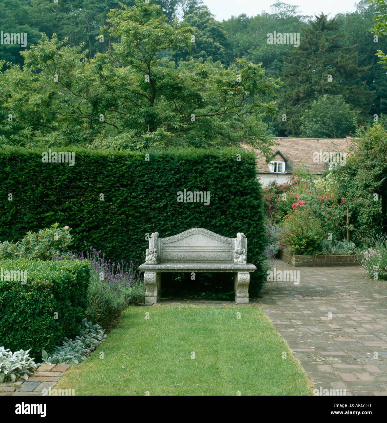 Restringere prato accanto sentiero lastricato che conduce al sedile in pietra di fronte tagliata yew hedge nel paese grande giardino Foto Stock