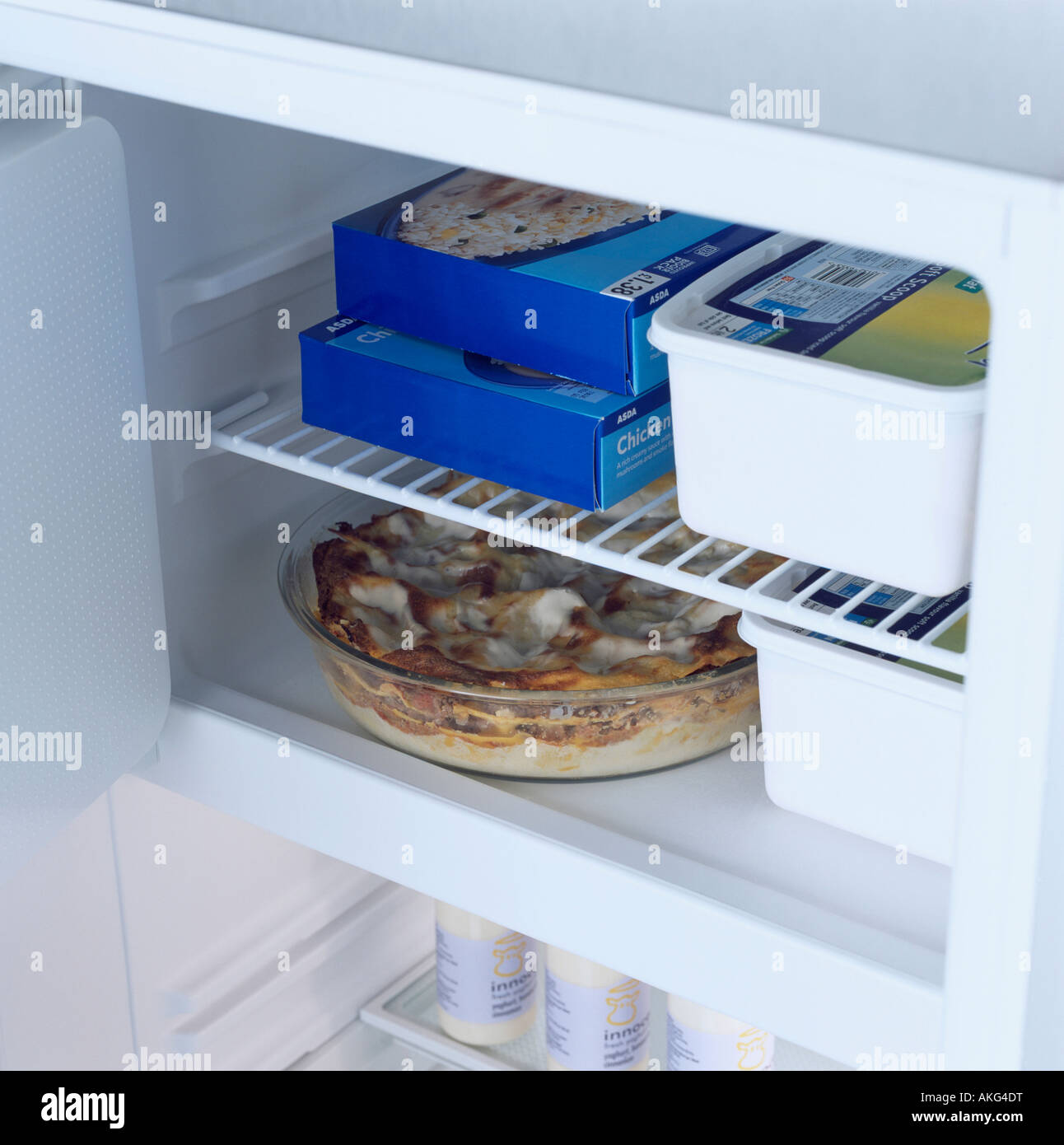 Chiusura del frigorifero con la porta aperta e il cibo in contenitori sugli scaffali Foto Stock