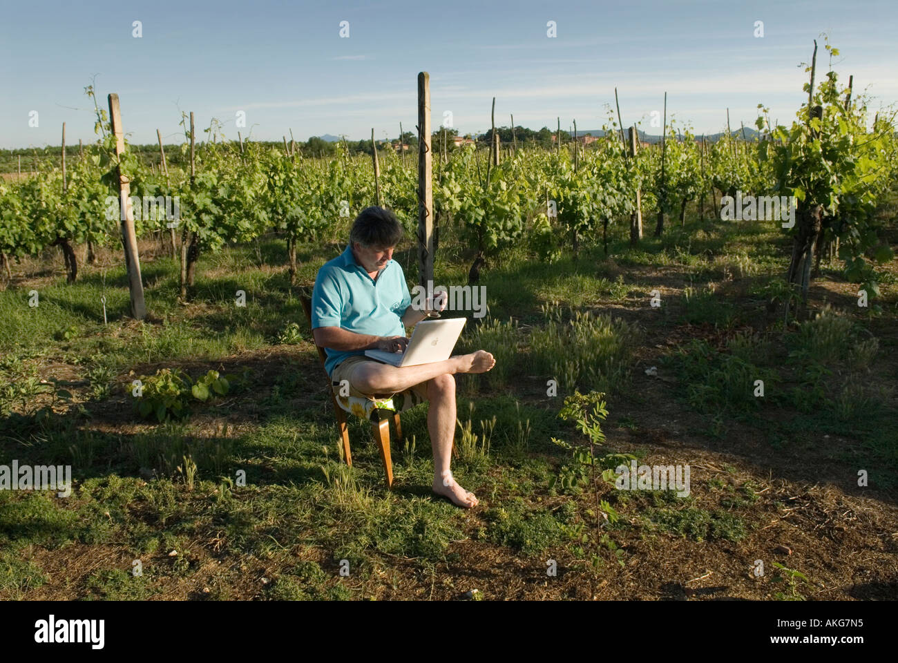Uomo al lavoro con computer lap top presso un cantiere di vite e AGRITURISMO IN TOSCANA ITALIA Foto Stock