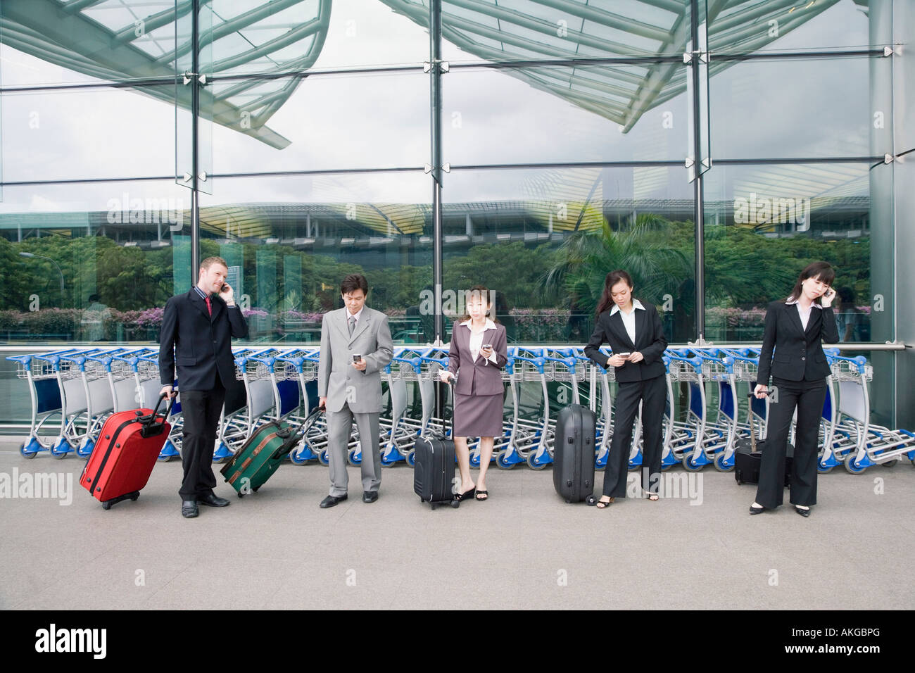 Tre imprenditrici con due imprenditori in attesa presso un aeroporto Foto Stock