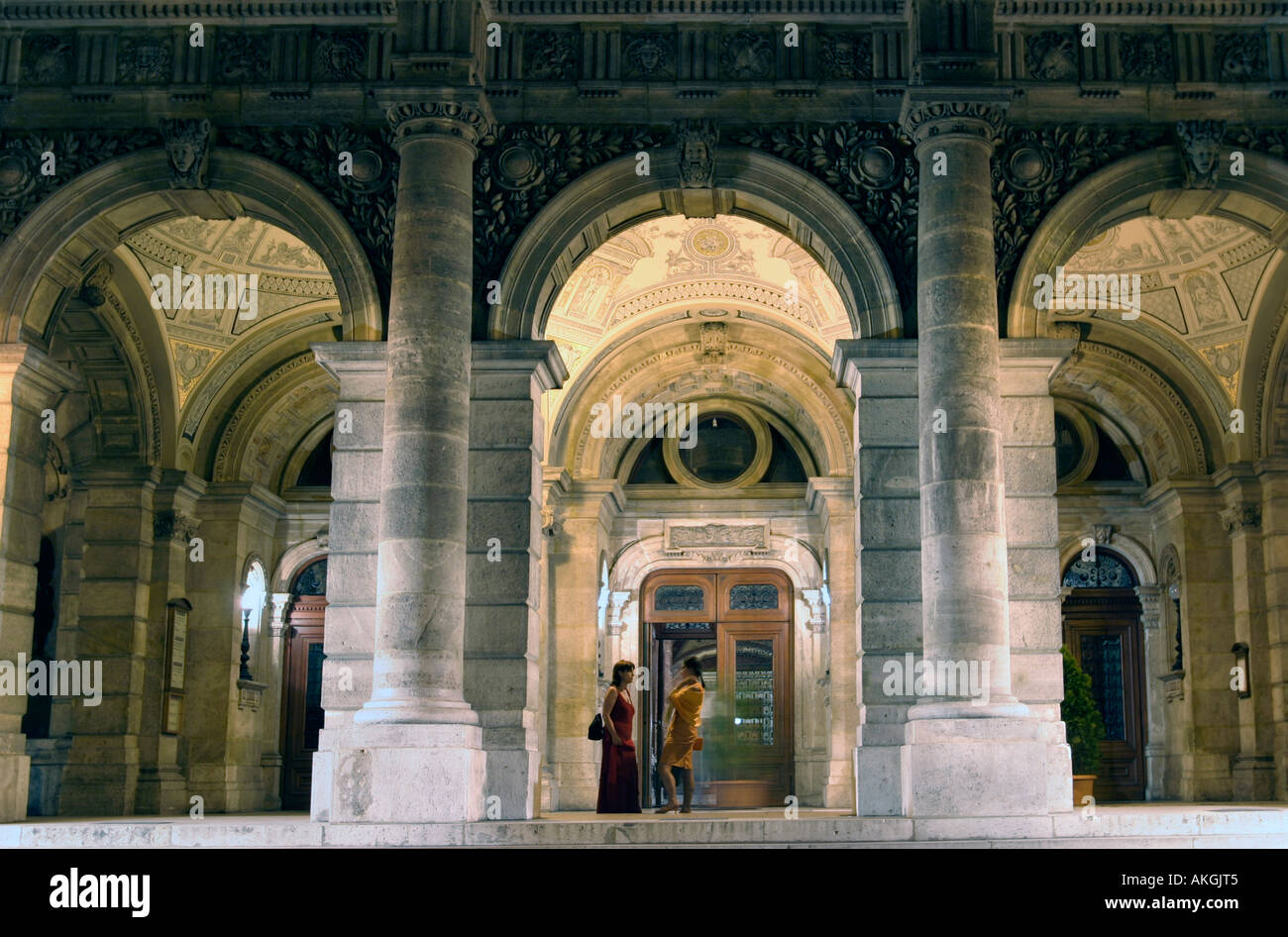 Due donne aventi una conversazione sotto gli archi del Teatro dell'Opera di notte Budapest Ungheria Foto Stock