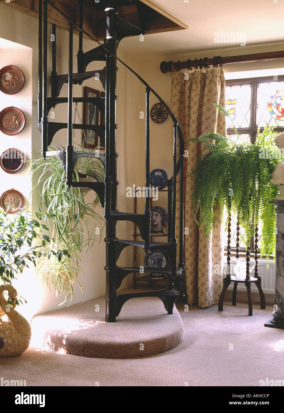 Ferro battuto scala a spirale nella piccola sala con Boston Fern sul tavolo da giardino Foto Stock