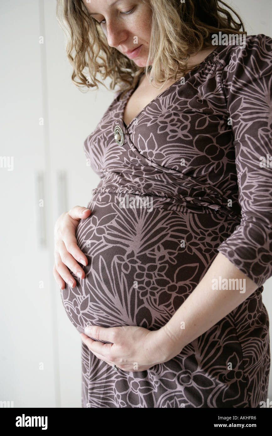 Donna incinta guardando il suo bump Foto Stock