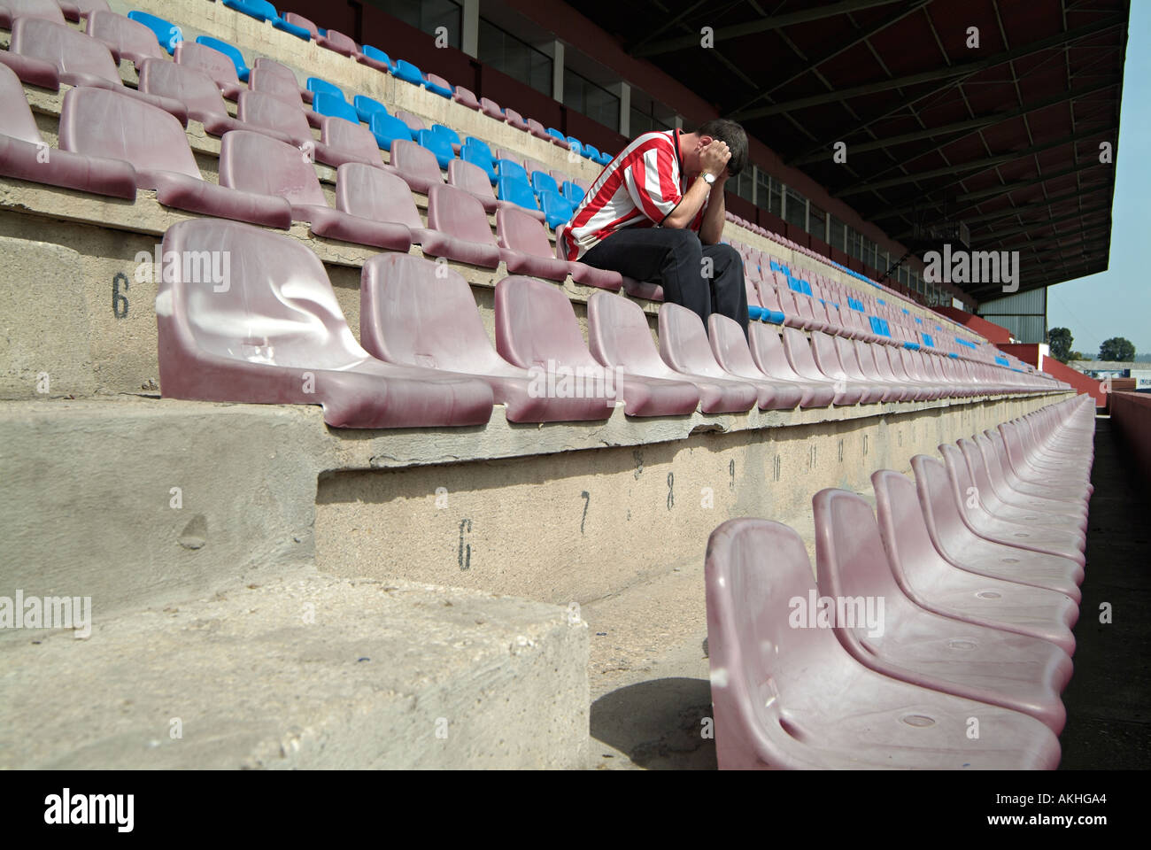 Premuto Football Soccer sostenitore seduto da solo in uno stadio vuoto dopo aver visto il suo team allentato. Foto Stock