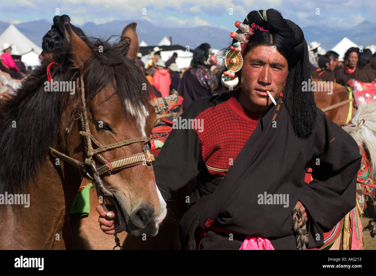 Khampa uomo pony tibetano attendere per avere la possibilità di correre al Litang Horse Festival Kham nella provincia del Sichuan in Cina Tibet Foto Stock