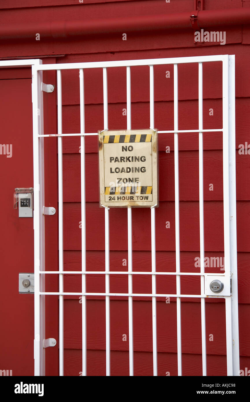 Nessun parcheggio zona di carico 24 ore di traino di un cartello di segnalazione fissato alla protezione in metallo porta con serratura e tastierino numerico Foto Stock
