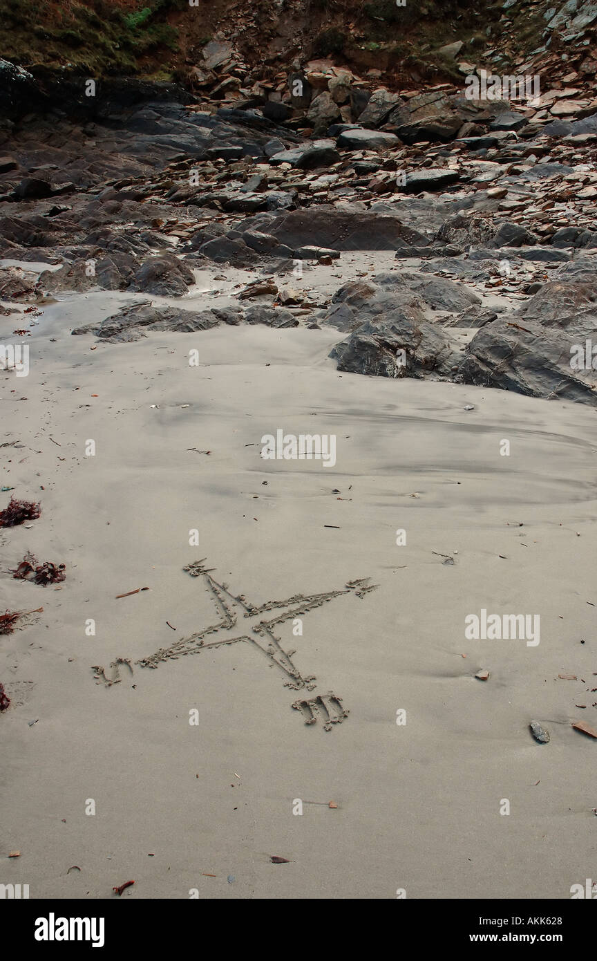 Compass disegnato in sabbia bagnata rocky seashore Foto Stock
