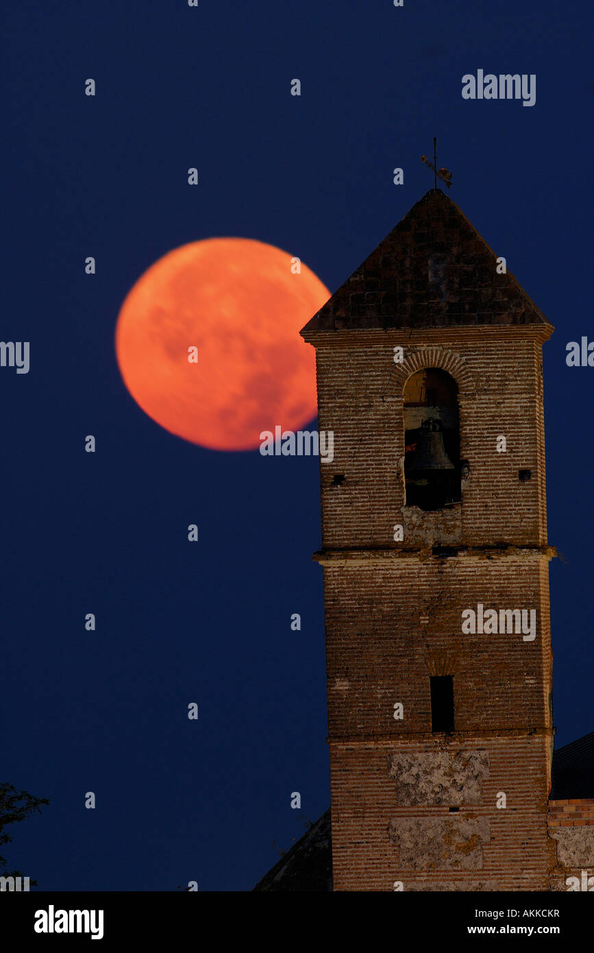 Luna piena di andare verso il basso dietro il campanile di una chiesa in montagna bianca villaggio di Casares , Andalusia , Spagna Foto Stock