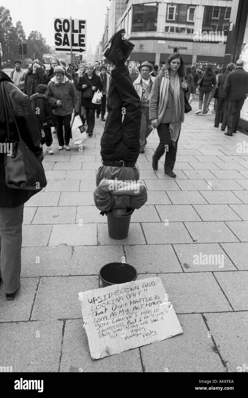 Un uomo in piedi a testa in giù con la sua testa in una benna Foto Stock