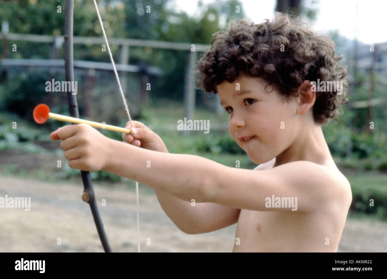 Un giovane ragazzo che sembra un cherubino su St. San Valentino sparando un arco giocattolo e una freccia in 1980s Lantzville British Columbia, Canada KATHY DEWITT Foto Stock