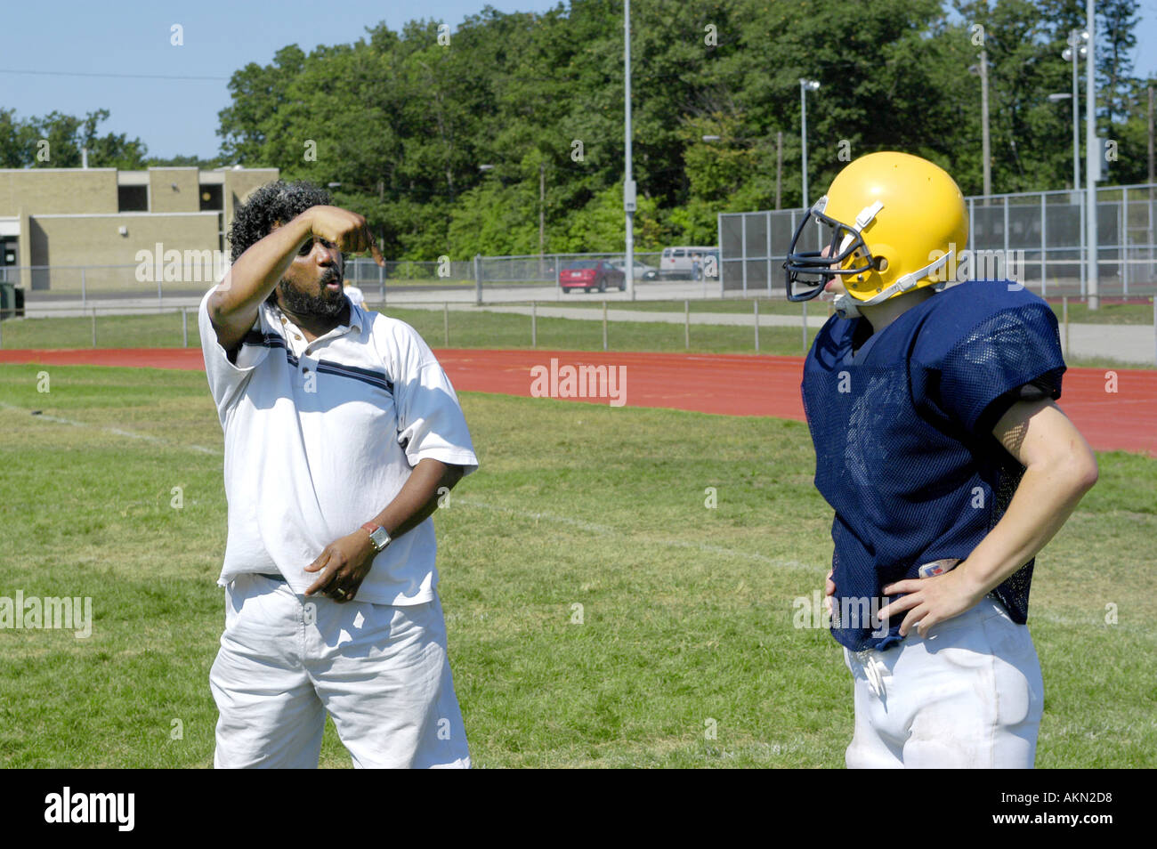 Alta Scuola Calcio azione Port Huron Michigan sordi JV giocatore di football legge la lingua dei segni data dal nero aiuto durante la pratica Foto Stock