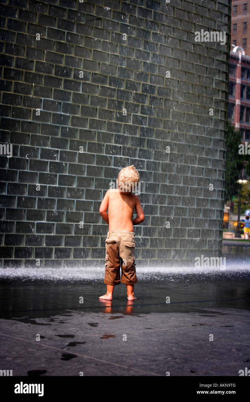 Un ragazzo in piedi accanto a una fontana a muro, Chicago, Illinois, Stati Uniti d'America Foto Stock