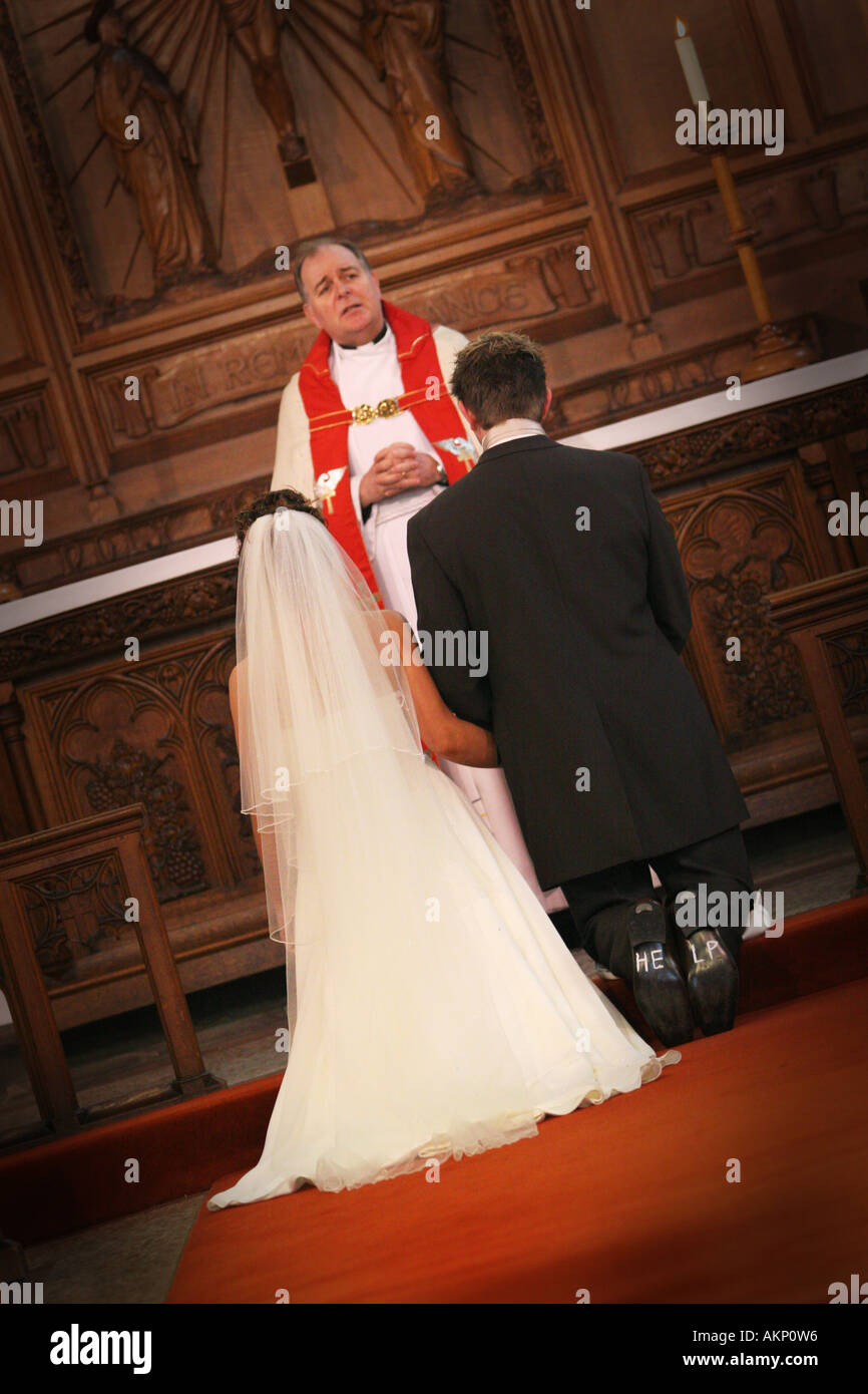 Lo sposo con aiuto scritto su suole di calzature si inginocchia all altare  durante la chiesa cattolica cerimonia di nozze UK funny divertente Foto  stock - Alamy
