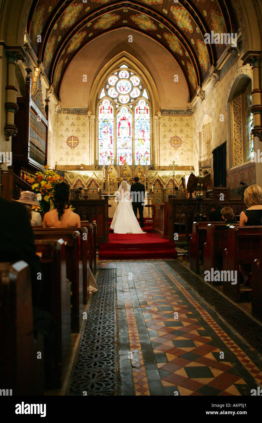 La sposa e lo sposo in abbigliamento tradizionale stand presso l'altare durante la loro cerimonia di nozze UK ritratto eretta verticale Foto Stock