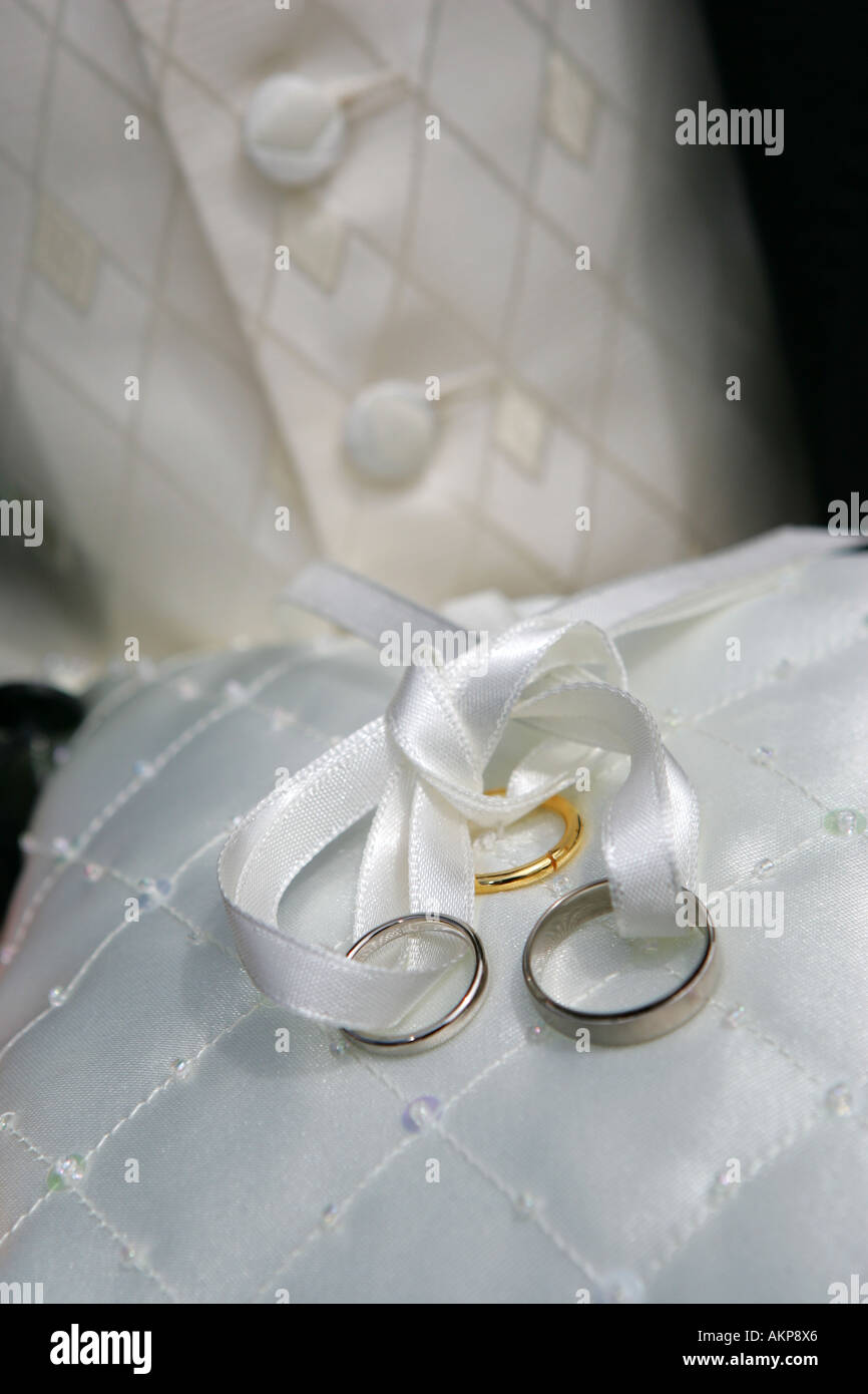 Primo piano i dettagli di una sposa e sposi fedi anelli oro bianco platino su un bianco ricamato cuscino di seta UK Gran Bretagna Foto Stock