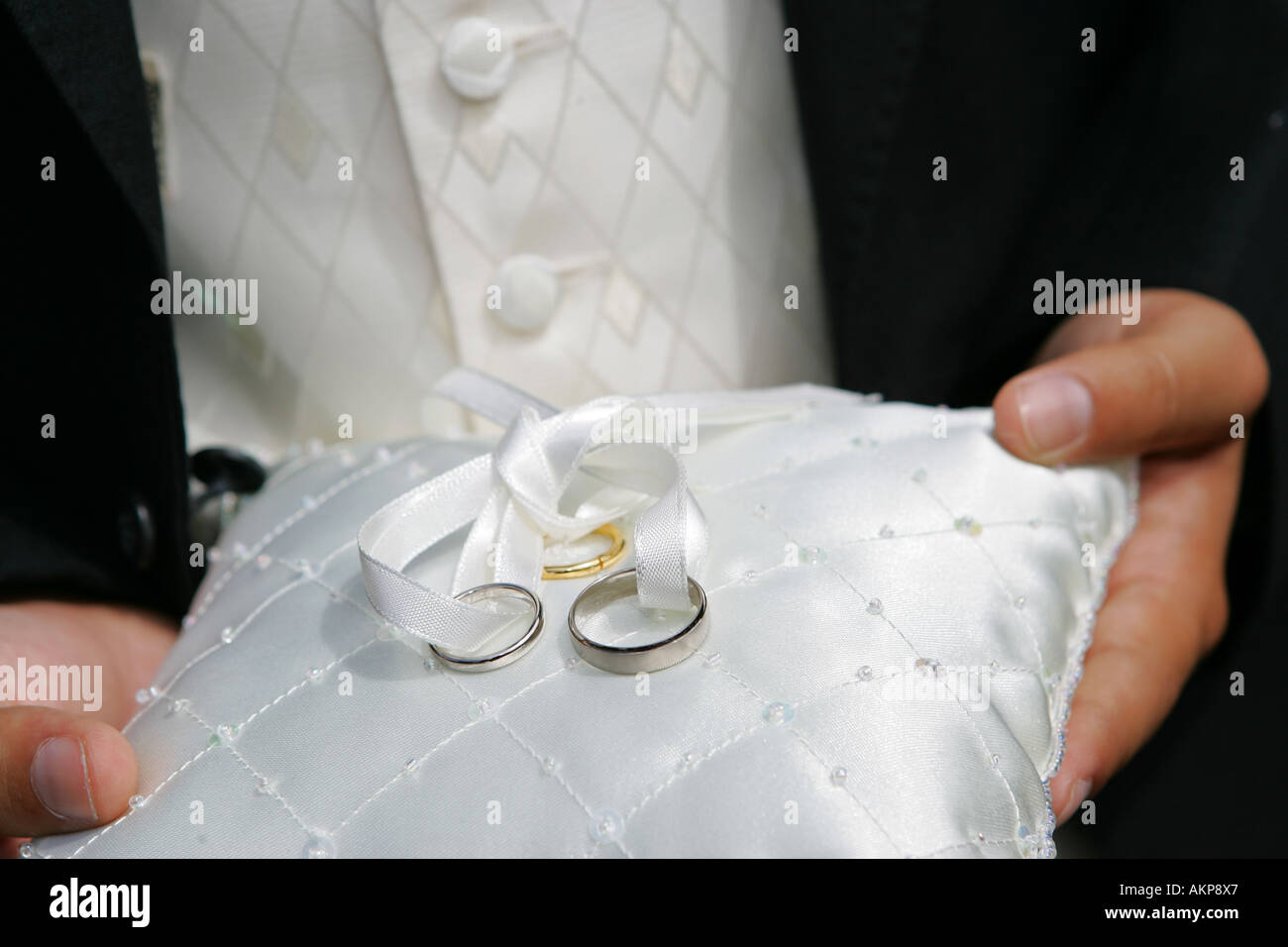 Primo piano i dettagli di una sposa e sposi fedi anelli oro bianco platino su un bianco ricamato cuscino di seta UK Gran Bretagna Foto Stock