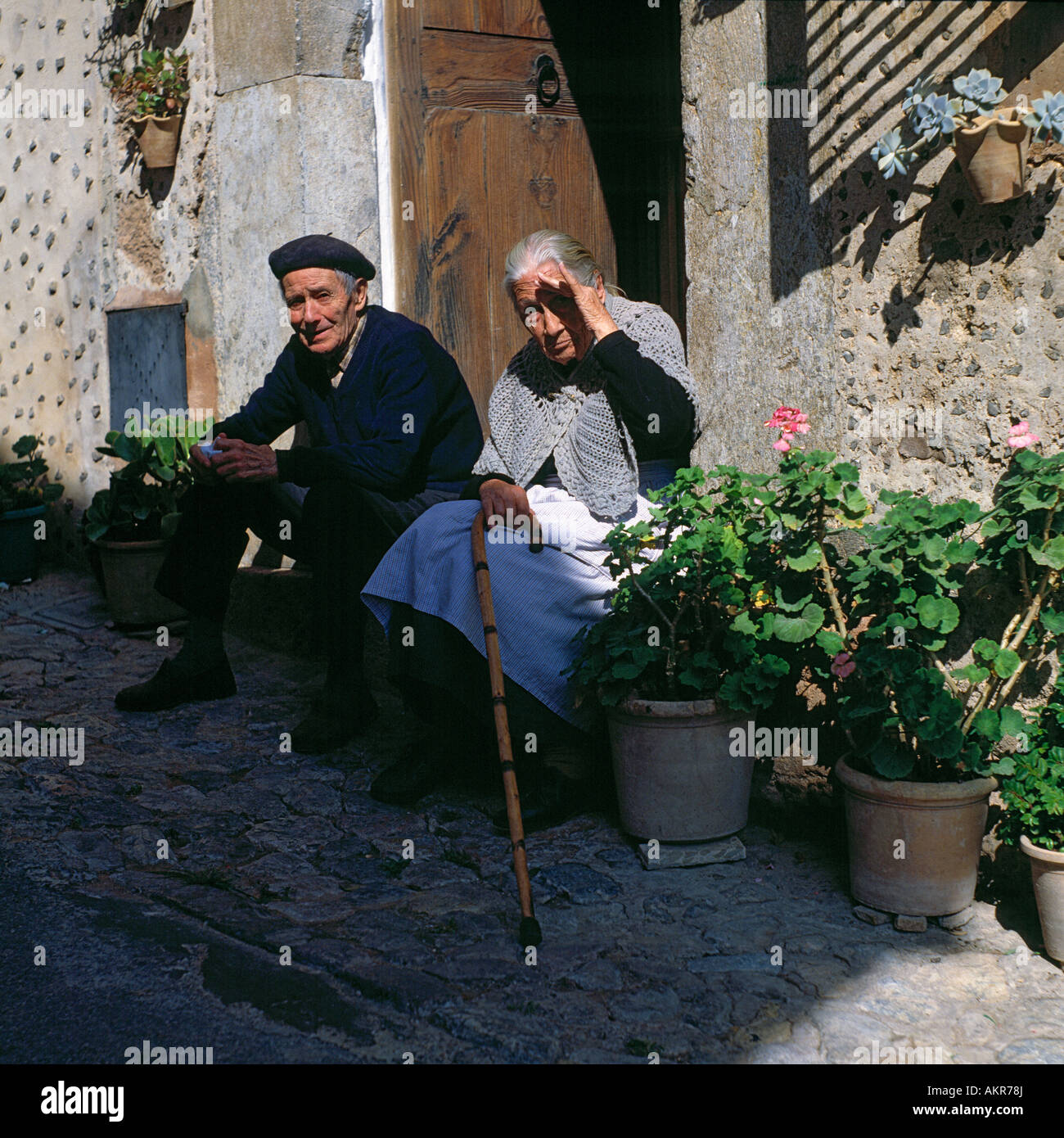 Isole Baleari Spagna, Maiorca, estate, calore, calore, senior giovane seduto di fronte a loro casa vecchia donna e vecchi uomini seduti all'ombra Foto Stock