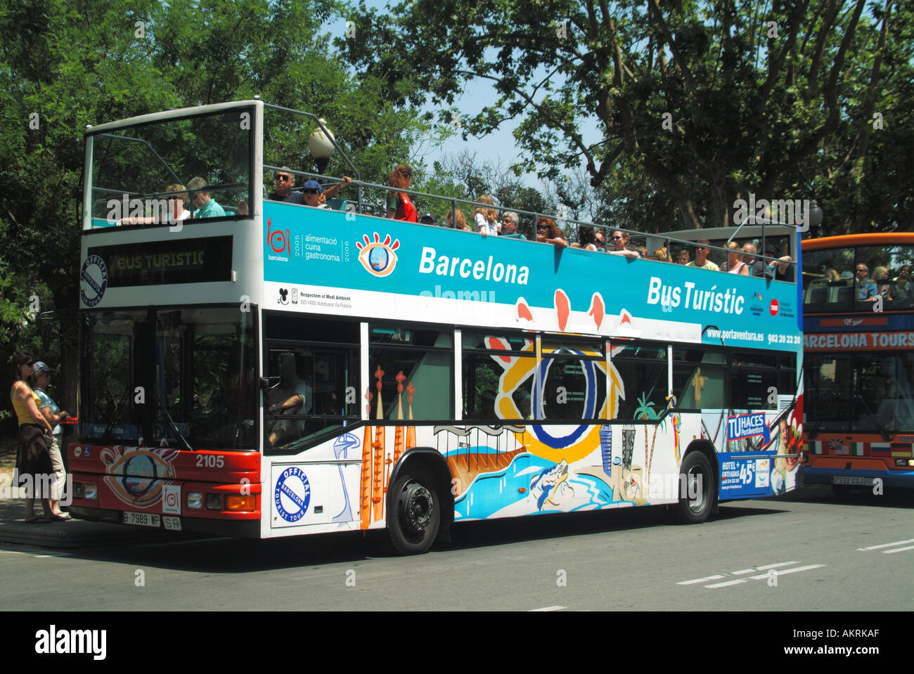 Passeggeri turistici seduti sul piano superiore di due autobus scoperto a due piani fuori dal complesso commerciale e caffetteria "Spanish Village" di Barcellona, Spagna Foto Stock