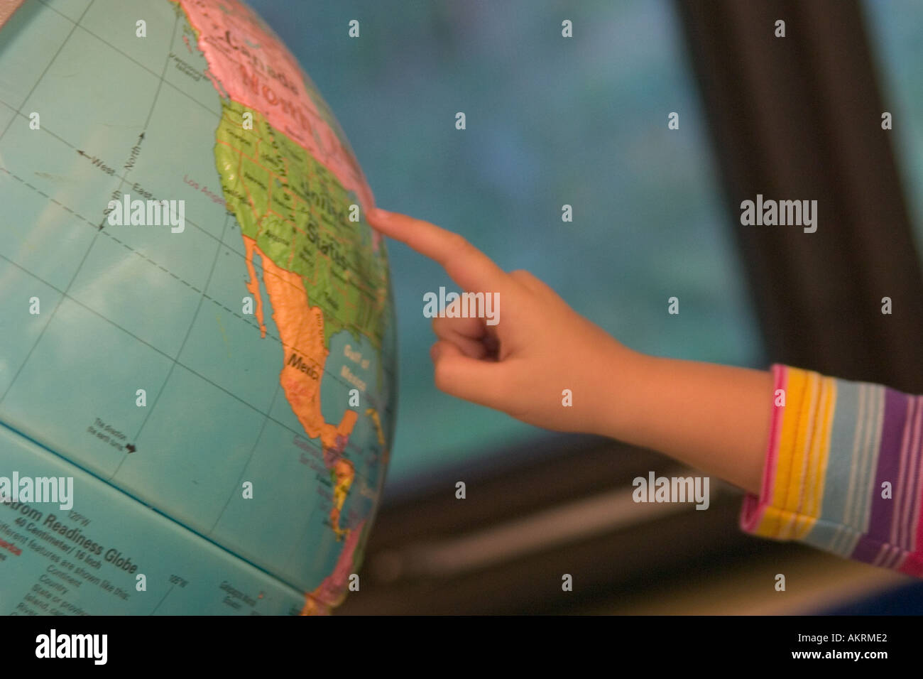 In prossimità di una giovane ragazza di puntamento a mano ad un globo mondo in un ambiente scolastico Foto Stock