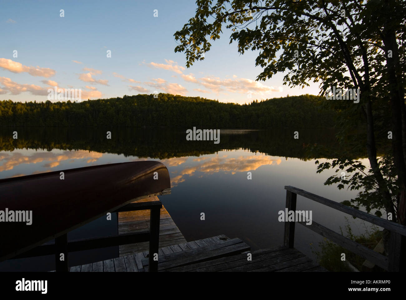 Immagine di stock di canoa sul dock al tramonto con le nuvole che riflettono nelle calme acque del lago New Brunswick Canada Foto Stock