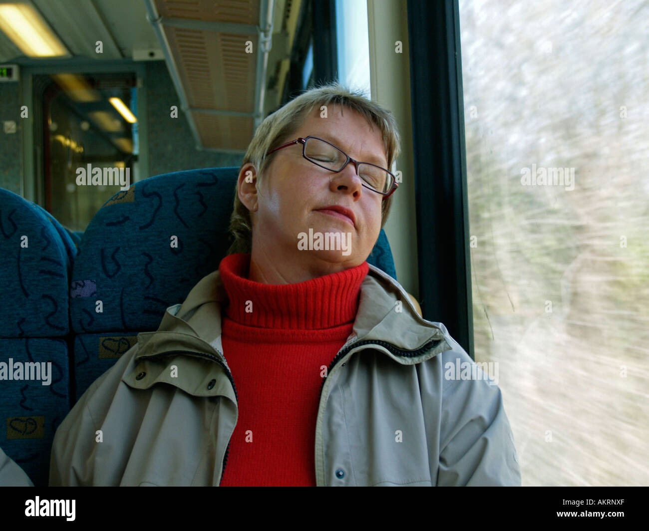Donna di mezza età seduta in un treno dormendo avente un pisolino Foto Stock