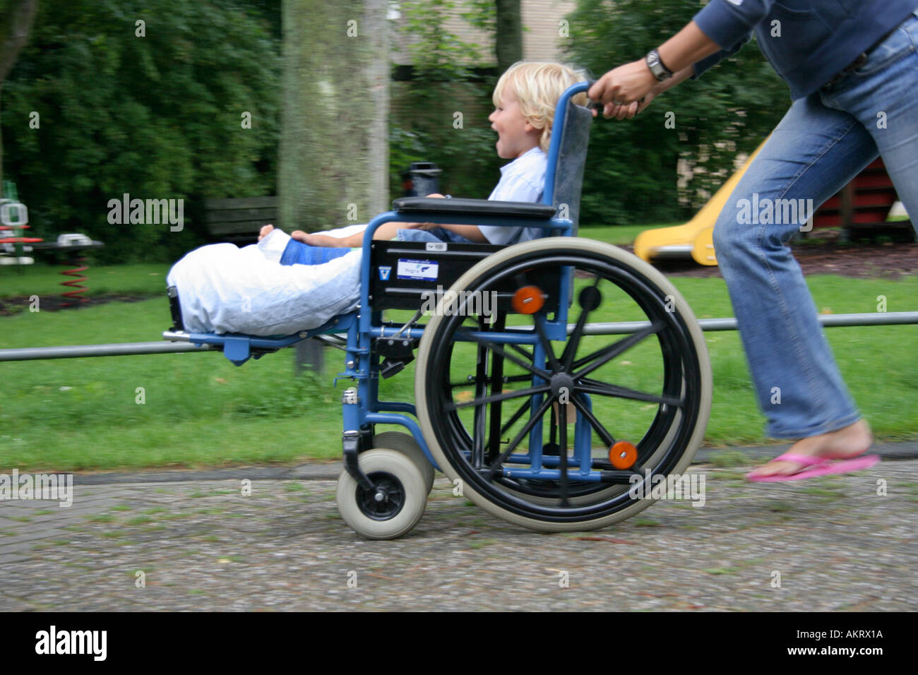 Ragazzino con una gamba rotta seduto in una sedia a rotelle Foto Stock