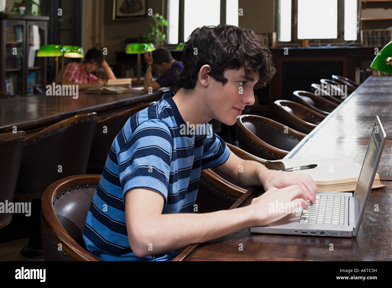 Boy utilizzando un computer portatile in biblioteca Foto Stock