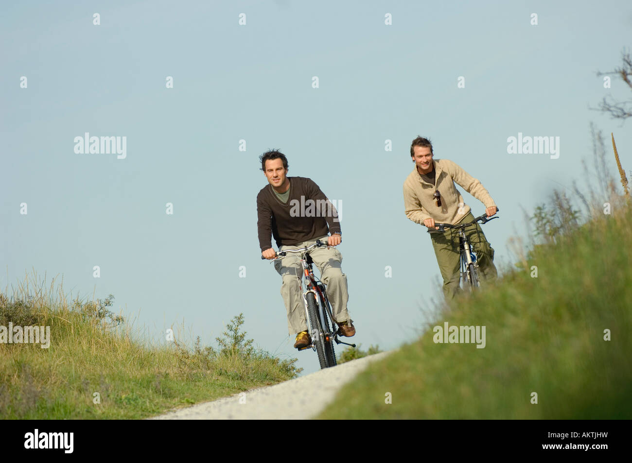 Due amici in bicicletta attraverso le dune, divertendosi Foto Stock