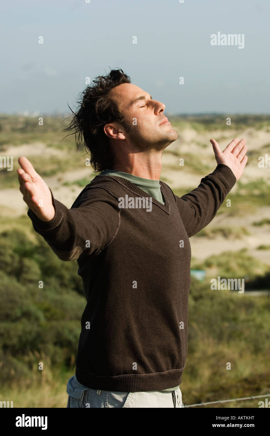 Uomo in piedi con le braccia distese di dune, vista laterale Foto Stock