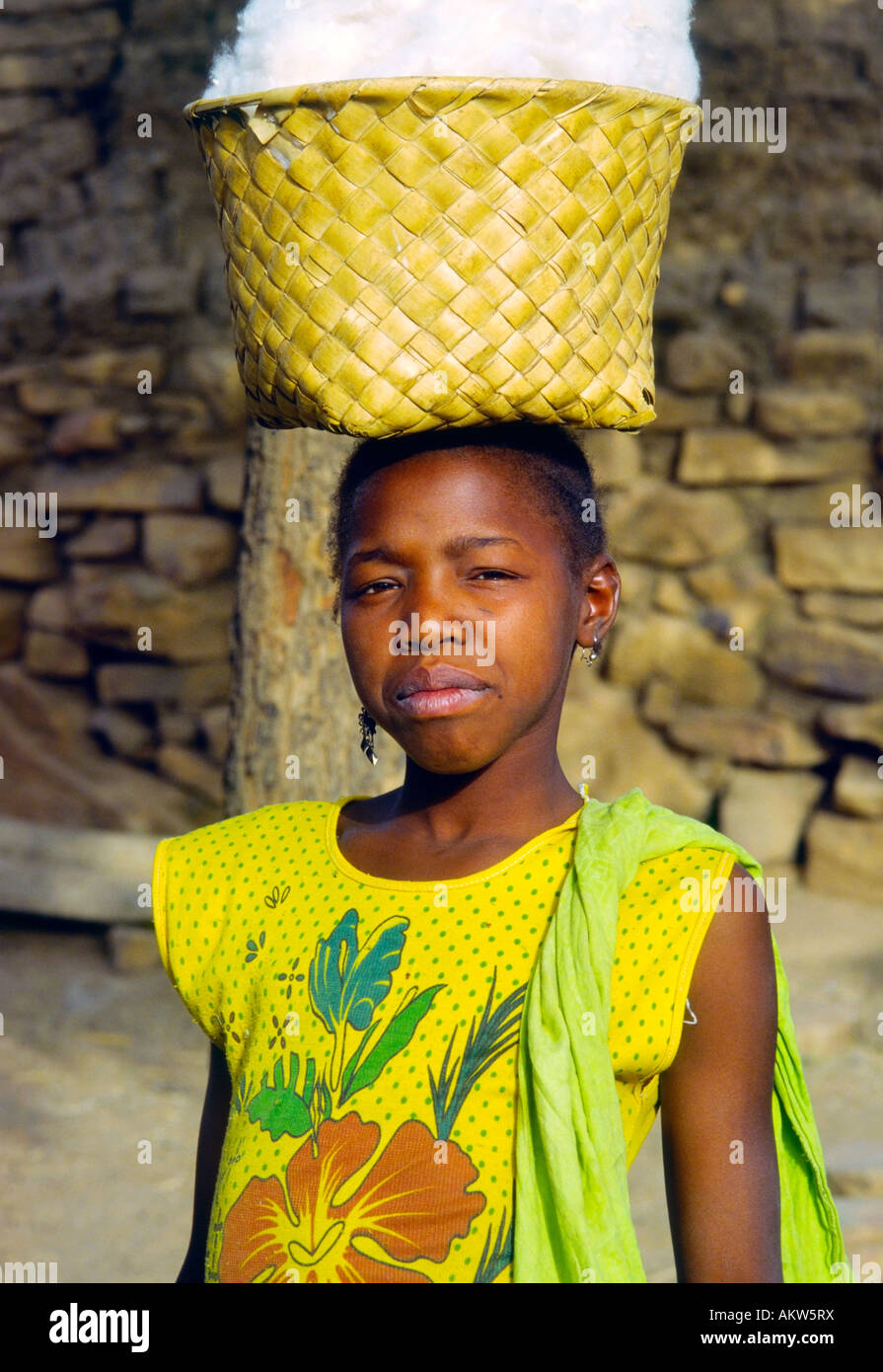 Una giovane donna saldi un cestello di cotone sul suo capo nel villaggio Dogon del Mali Tougoume Foto Stock