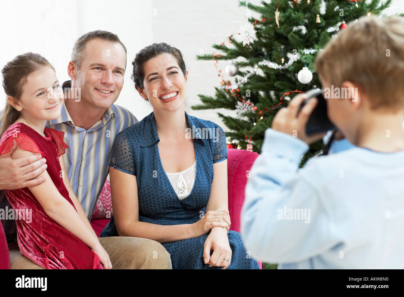 Ragazzo prendendo foto di sitter il padre e la madre da albero di natale Foto Stock
