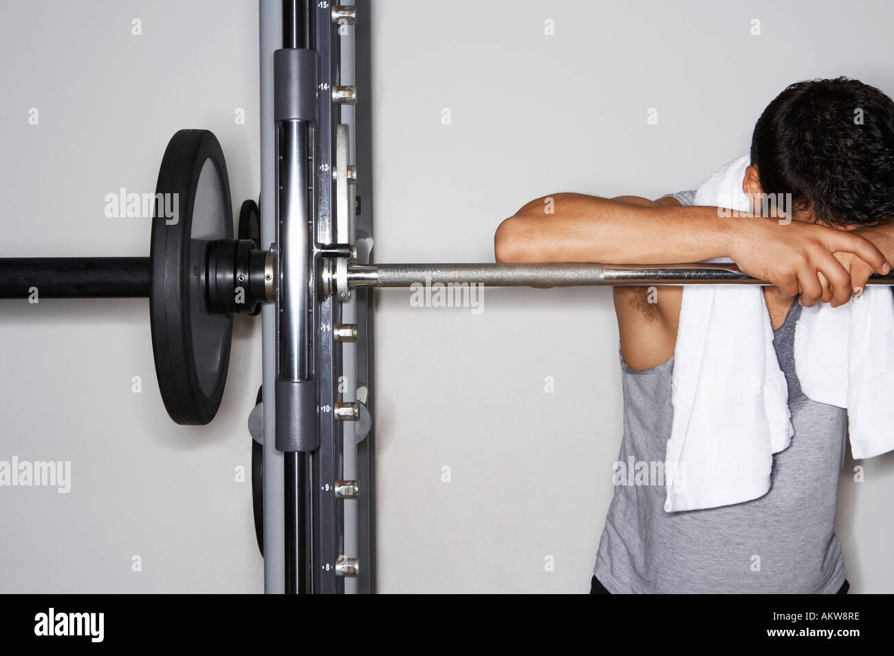 Sudati uomo appoggiato su barbell dopo allenamento Foto Stock