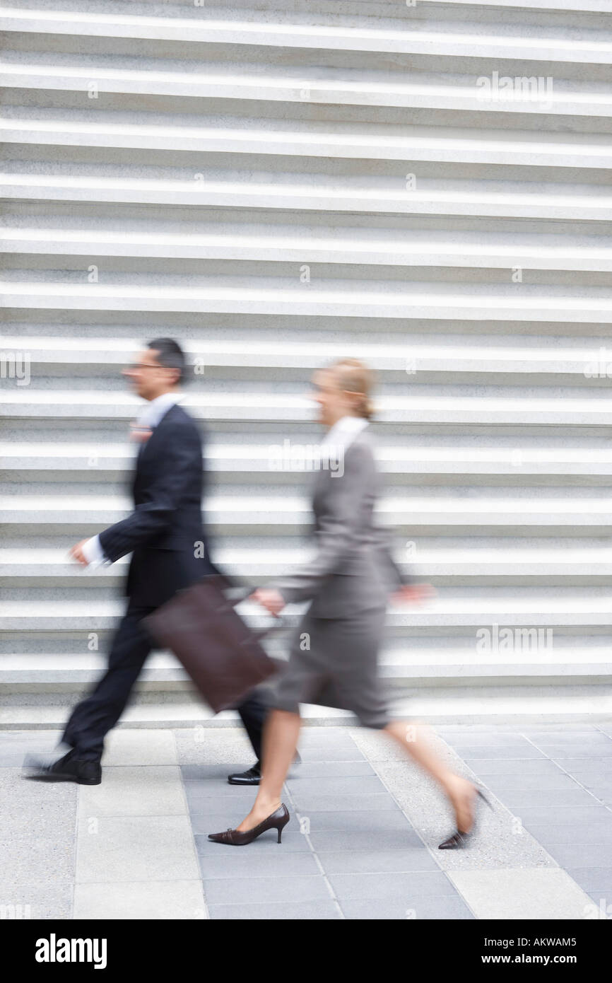 Imprenditore e imprenditrice camminare velocemente, vista laterale Foto Stock