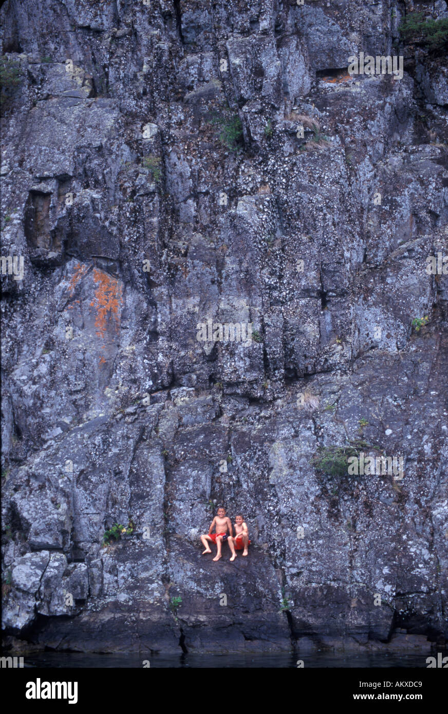 Twin boys tuffarsi e nuotare off parete di roccia in Lake George New York Foto Stock