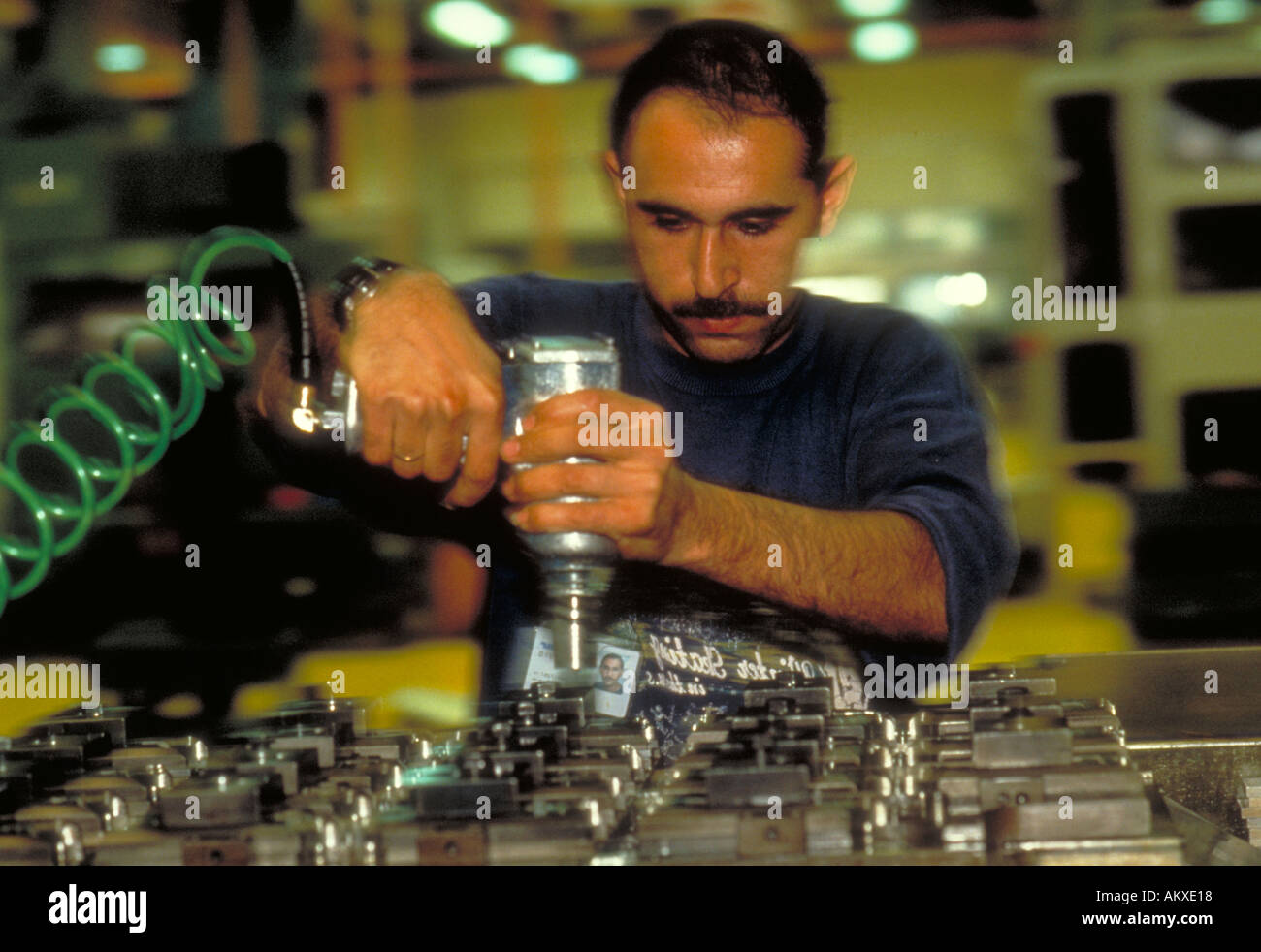 Un operaio di fabbrica lavora su macchinari con un utensile elettrico. Foto Stock