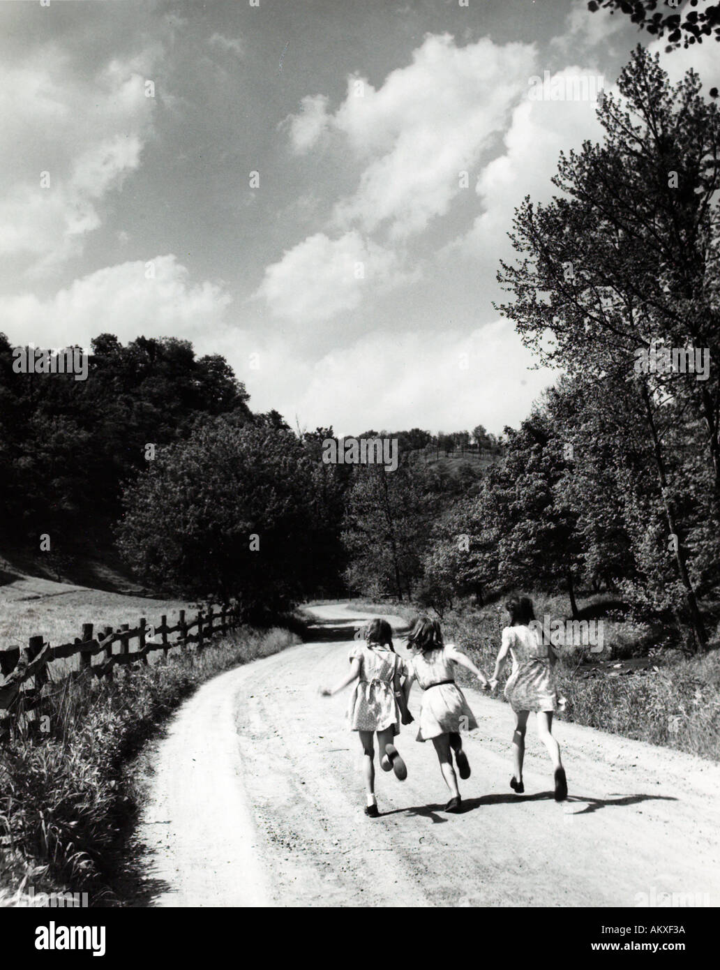 Tre giovani ragazze correre giù country road 1950 s Foto Stock