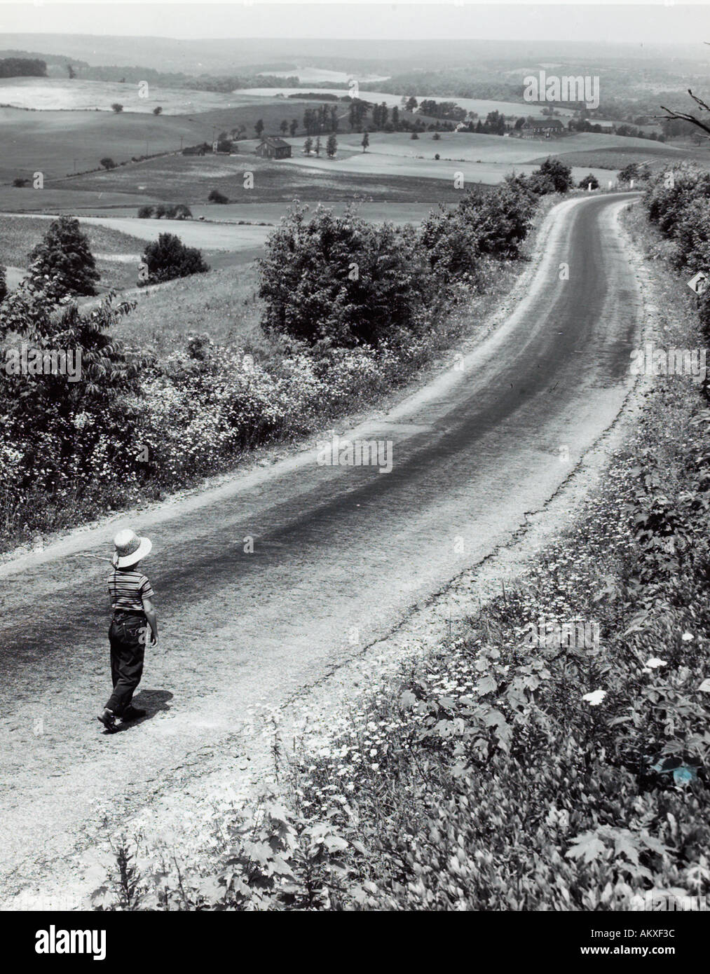 Bambino camminando sulla lunga strada di campagna 1950 s Foto Stock