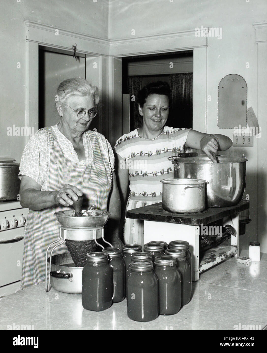 Due donne inscatolando verdura in cucina 1950 s Foto Stock