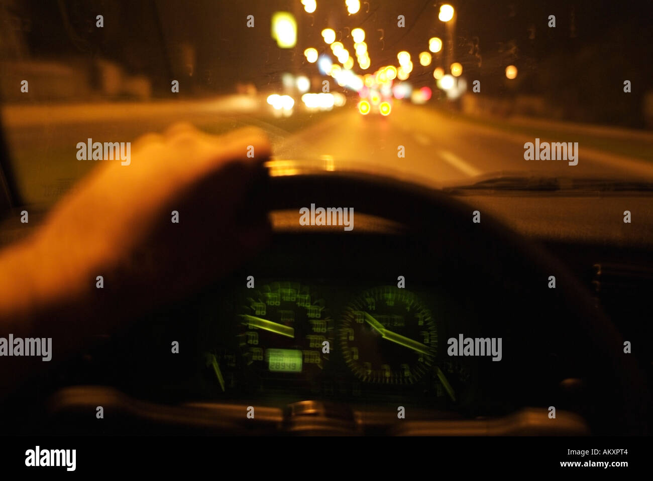 Driver vista dall'interno di un Guida auto di notte lungo una strada della città Foto Stock