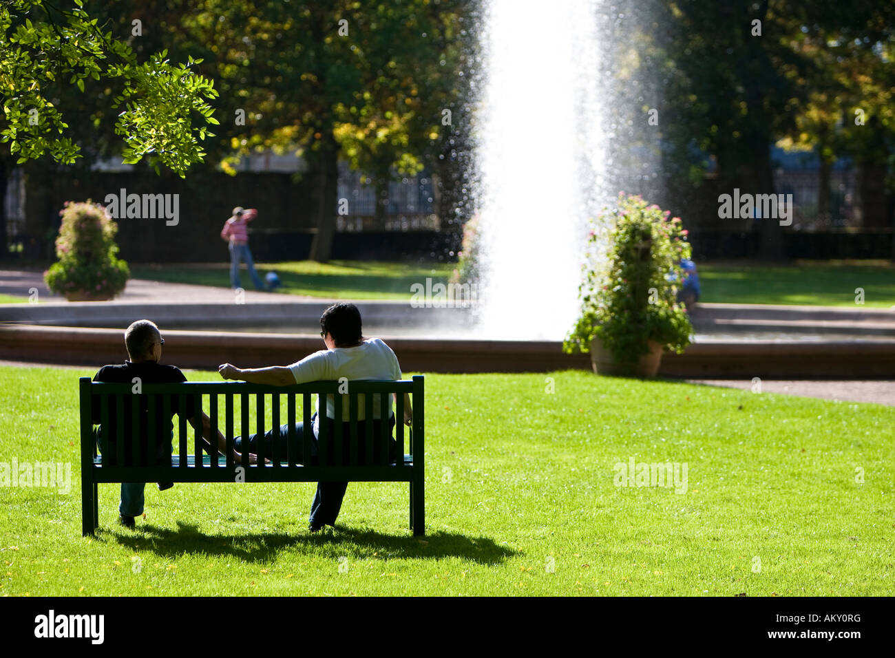 Persone in un parco seduta su una panchina di fronte a una fontana, Hesse, Germania Foto Stock