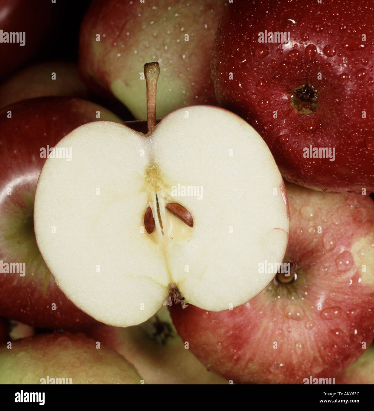 Close up di mele rosse con uno tagliate a metà con discreti goccioline di acqua sulla frutta Foto Stock