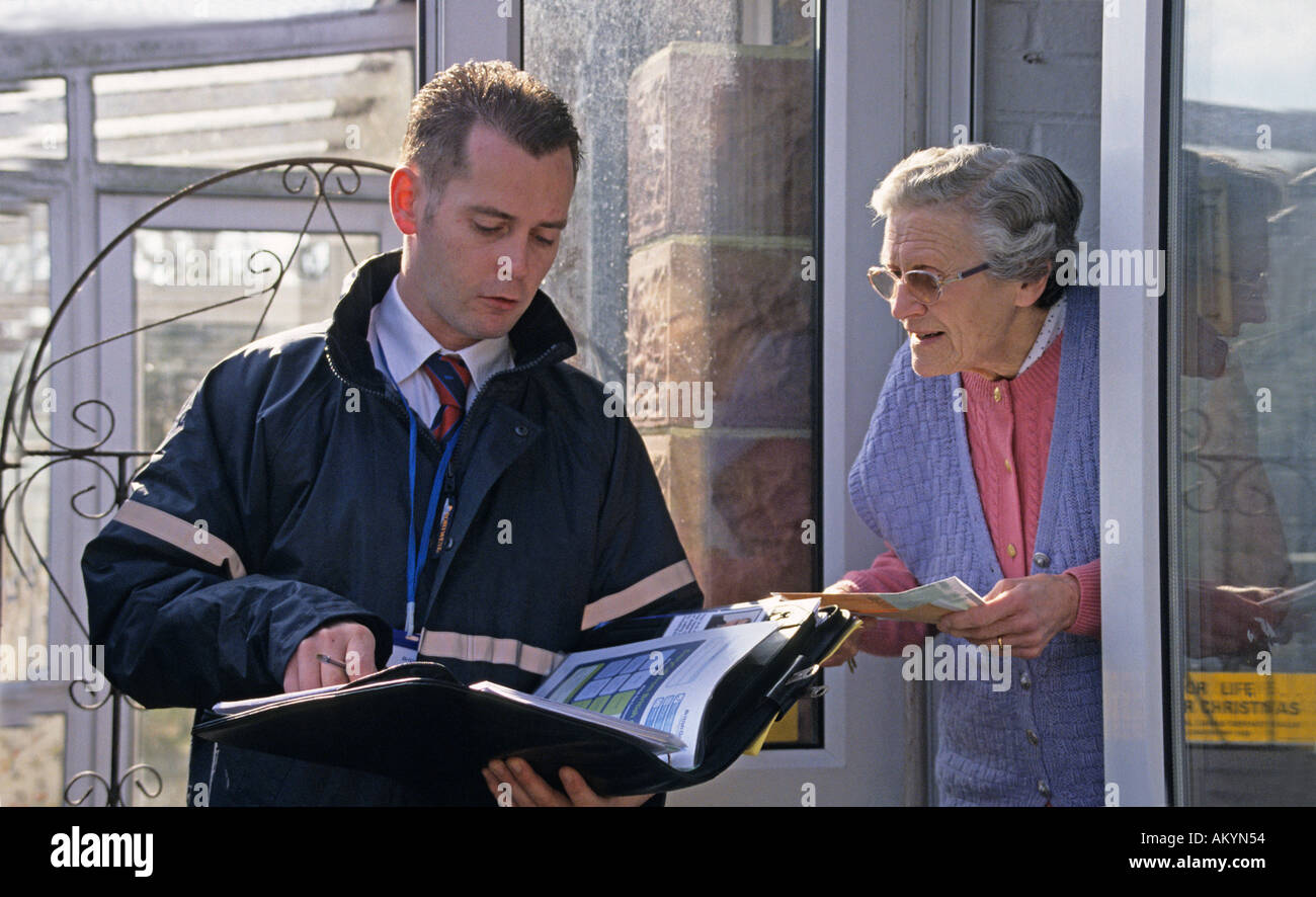 Da porta a porta venditore parlando di donna anziana Foto Stock