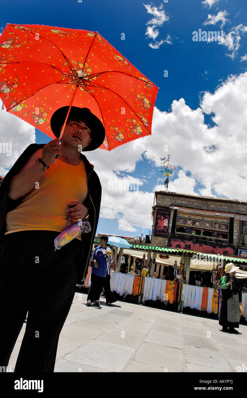 Uomo cinese con sun parasol sulla piazza Barkhor, Lhasa, in Tibet Foto Stock