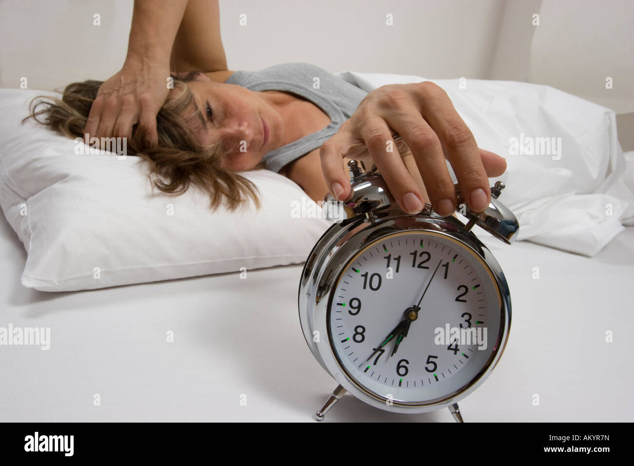 La donna a letto, spegnendo la sveglia Foto Stock