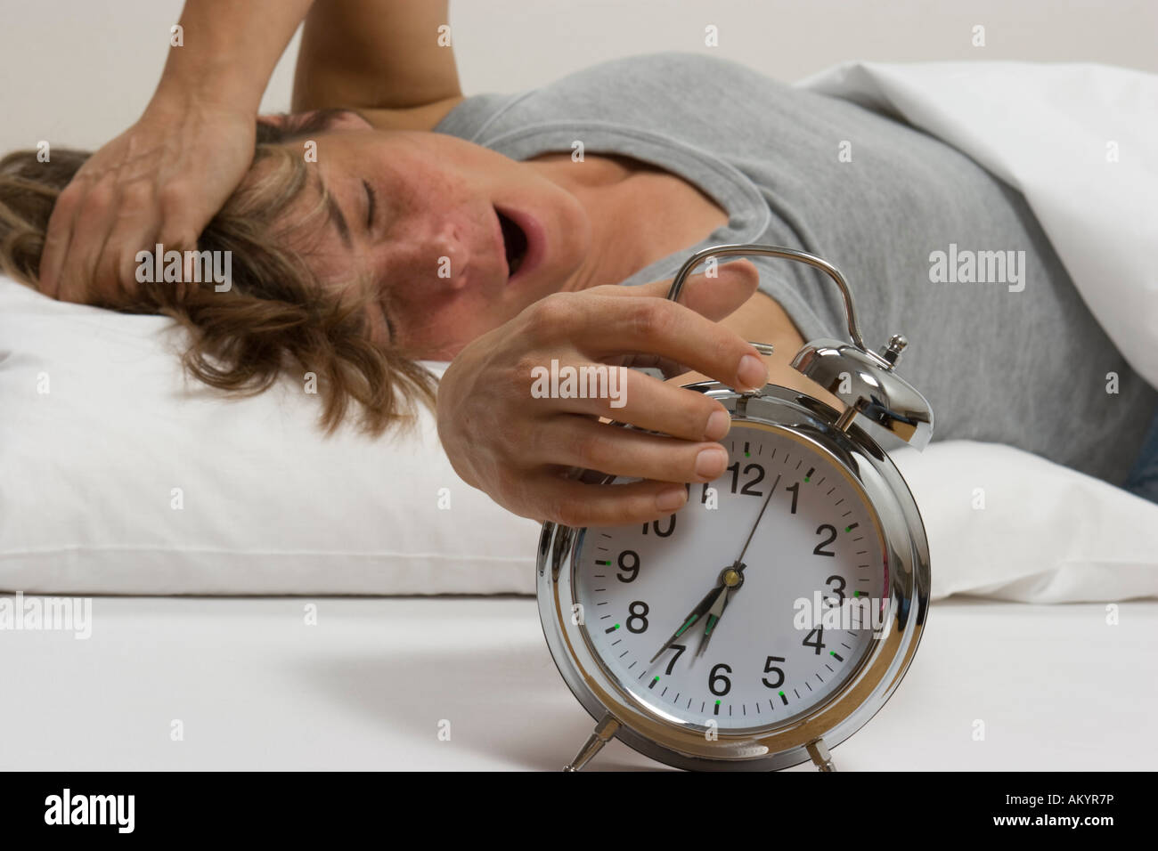 La donna a letto, spegnendo la sveglia Foto Stock