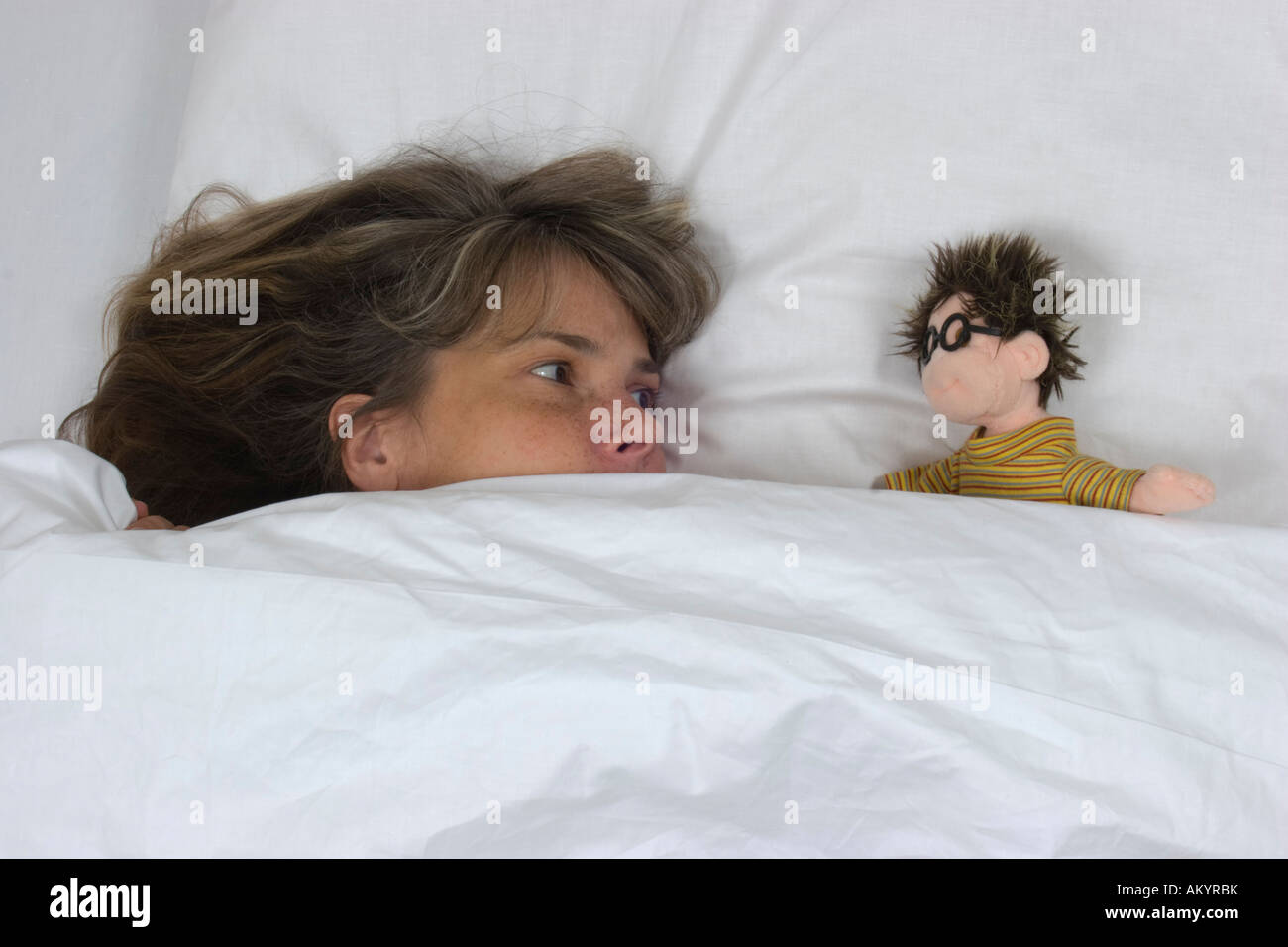 Donna con una bambola in letto Foto Stock